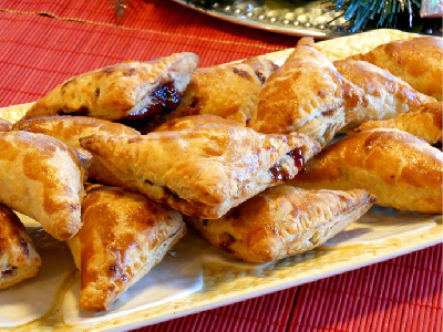 Raspberry puff pastries on a white rectangular plate sitting on a red table cloth.
